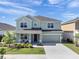 Two-story home featuring a front porch, well-maintained lawn, and an attached two car garage at 871 Fillmore Ct, Davenport, FL 33837