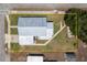 Aerial view of home displaying the metal roof, concrete driveway, walkway, green grass, and mature trees around the property at 101 S Cleveland Ave, Fort Meade, FL 33841