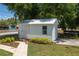 A white shed with a door and window, landscaped with green and yellow bushes at 101 S Cleveland Ave, Fort Meade, FL 33841