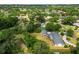 Wide aerial shot of a wooded neighborhood featuring a home with a pool nearby at 1205 Rolling Woods Ln, Lakeland, FL 33813