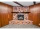 Close up of living room brick fireplace and wood-paneled walls with neutral carpet at 1205 Rolling Woods Ln, Lakeland, FL 33813