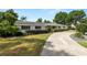 Beautiful single-story home with a circular driveway, lush landscaping, and manicured lawn at 1205 Rolling Woods Ln, Lakeland, FL 33813