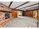 Living room featuring wood-paneled walls, brick fireplace, beamed ceiling, and neutral carpet at 1205 Rolling Woods Ln, Lakeland, FL 33813