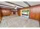 Cozy living room featuring a brick fireplace, wood paneling, plush carpet, and access to a screened-in porch at 1205 Rolling Woods Ln, Lakeland, FL 33813