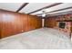 Cozy living room with wood-paneled walls, brick fireplace, beamed ceiling, and neutral carpet at 1205 Rolling Woods Ln, Lakeland, FL 33813