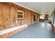 Covered patio featuring wood paneling, gray flooring and a pass-through to the brick oven at 1205 Rolling Woods Ln, Lakeland, FL 33813