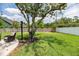 A nicely landscaped backyard with a white fence, lush grass, a mature tree and a concrete patio at 1536 Del Crest Pl, Lakeland, FL 33803