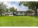 Spacious backyard featuring a lush green lawn, patio furniture, and mature trees, perfect for outdoor entertaining at 1536 Del Crest Pl, Lakeland, FL 33803