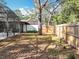 A spacious backyard next to a screened-in pool with a tree, wooden fence, and other natural foliage at 203 N Sweetwater Blvd, Longwood, FL 32779