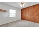 Inviting bedroom featuring textured wood paneling, a window for natural light, and cozy carpet at 209 S Hydrangea Ave, Polk City, FL 33868