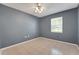 A cozy bedroom with light gray walls, beige tile flooring, and natural light from the window at 209 S Hydrangea Ave, Polk City, FL 33868