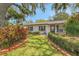 Inviting home exterior featuring manicured lawn, mature trees, and lush landscaping at 209 S Hydrangea Ave, Polk City, FL 33868