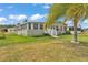 Exterior home view showcasing green siding, red shutters, a well-manicured lawn, and a glimpse of surrounding foliage at 2101 Cypress Cross Dr, Lakeland, FL 33810