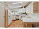 Kitchen featuring white cabinets, white appliances, wood flooring, and access to a door and window at 211 Sweet Cir, Winter Haven, FL 33884