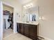 Stylish bathroom with double sinks, dark cabinetry, and a walk-in closet that offers ample storage space at 2112 Betsy Ross Ln, St Cloud, FL 34769