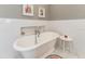 White bathtub with chrome fixtures sits beneath floral artwork, creating a soothing spa-like setting at 2115 W Pipkin Rd, Lakeland, FL 33811