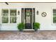 Elegant front door with glass details, flanked by ferns, and a decorative 'S' on the white siding at 2115 W Pipkin Rd, Lakeland, FL 33811