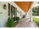 Charming porch with brick floors, wood ceiling, black rocking chairs, and plants by the front door at 2115 W Pipkin Rd, Lakeland, FL 33811