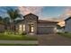 Inviting home exterior featuring a stone facade, tile roof, landscaped yard, and brick driveway at 2277 Bella Luna Cir, Lakeland, FL 33810