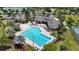 Aerial view of a community pool area with palm trees, lounge chairs, and tennis courts nearby at 2468 Winnipeg Dr, Lakeland, FL 33805