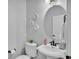 Bathroom features an oval mirror, white flowers, a small plant, and a pedestal sink at 2468 Winnipeg Dr, Lakeland, FL 33805