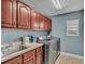 Well-equipped laundry room with wooden cabinets, a utility sink, stainless steel washer and dryer, and a bright window at 2468 Winnipeg Dr, Lakeland, FL 33805