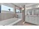 Modern bathroom featuring a soaking tub, glass-enclosed shower, and dual vanity with stone countertop at 2611 San Marco Way, Winter Haven, FL 33884
