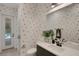 Stylish bathroom features unique wallpaper, a modern vanity, and a glass-enclosed shower at 2645 Delphi Hills Ct, Lakeland, FL 33812