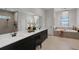 Bright ensuite bathroom featuring a dual sink vanity, a chandelier, and a soaking tub at 2645 Delphi Hills Ct, Lakeland, FL 33812
