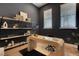 A modern home office features dark walls, wood floors, a wood desk and decorative shelving with window lighting at 2645 Delphi Hills Ct, Lakeland, FL 33812