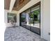 A covered patio area with an outdoor chair looks onto the yard and pool through sliding glass doors at 2645 Delphi Hills Ct, Lakeland, FL 33812
