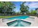 Backyard swimming pool has an attached spa, a dark metal safety fence, and green, grassy surroundings at 2645 Delphi Hills Ct, Lakeland, FL 33812