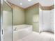 Bright bathroom featuring a shower, soaking tub with tile surround, and floral wallpaper border detail at 2820 Prestwick Dr, Lakeland, FL 33803
