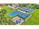 Aerial view showcasing tennis courts, pickleball court, basketball court and playground surrounded by lush green landscape at 3252 Bellflower Way, Lakeland, FL 33811