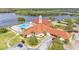 Aerial view of clubhouse with red roof, pool, and lake, complete with lush landscaping and parking area at 3252 Bellflower Way, Lakeland, FL 33811