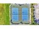 Aerial view of two blue outdoor tennis courts with green surrounds and black fence at 3252 Bellflower Way, Lakeland, FL 33811