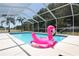 Relax in the screened-in pool with a playful flamingo float, surrounded by lush greenery and privacy at 3359 Sanoma Dr, Lakeland, FL 33811