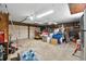 A cluttered garage with storage and tools, featuring a white garage door and fluorescent lighting at 3805 Gaines Dr, Winter Haven, FL 33884