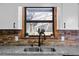 Charming kitchen sink area with a view from the window and complemented by stone backsplash at 3805 Gaines Dr, Winter Haven, FL 33884
