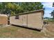 A tan shed with a window and door, accompanied by a small trailer, on a grassy lot at 3805 Gaines Dr, Winter Haven, FL 33884