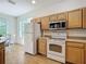 Well-lit kitchen with white appliances, wood cabinetry, and views into the adjacent dining area at 3852 Serenade Ln, Lakeland, FL 33811