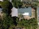 Aerial view of the home showcasing the green roof, spacious paved driveway, and surrounding mature trees at 3880 Cleveland Heights Blvd, Lakeland, FL 33813