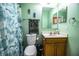 Bright bathroom featuring a vanity with wood cabinets, a large mirror, toilet, and shower with a decorative curtain at 3942 Warbler Dr, Winter Haven, FL 33880