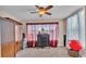 Bedroom featuring a ceiling fan, dresser, and large window with red curtains at 410 S Broadway Ave, Bartow, FL 33830
