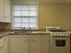 A simple kitchen with white cabinets, stainless steel sink, stove and ample natural light from the window at 422 E Belmar St, Lakeland, FL 33803