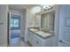 A bathroom featuring a granite countertop, dual sinks, modern faucets, and elegant vanity lighting at 535 Tanaro Ln, Haines City, FL 33844