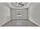 Expansive bedroom with wood-look tile flooring, trey ceiling with fan, and window view of the landscaped yard at 5512 Odom Rd, Lakeland, FL 33809