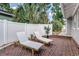 Brick patio with two lounge chairs, side table, and lush landscaping behind a privacy fence at 746 Mississippi Ave, Lakeland, FL 33801