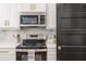 Close up of stainless oven, microwave, white cabinets, and black accent door with gold hardware at 746 Mississippi Ave, Lakeland, FL 33801