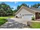 Back exterior view of home featuring a large garage, expansive yard, and mature trees at 930 Country Oaks Ln, Lakeland, FL 33810